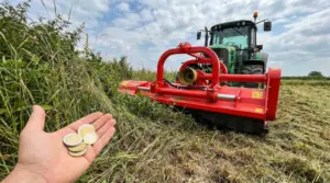 Trattore con trinciastocchi su campo e una mano che mostra monete