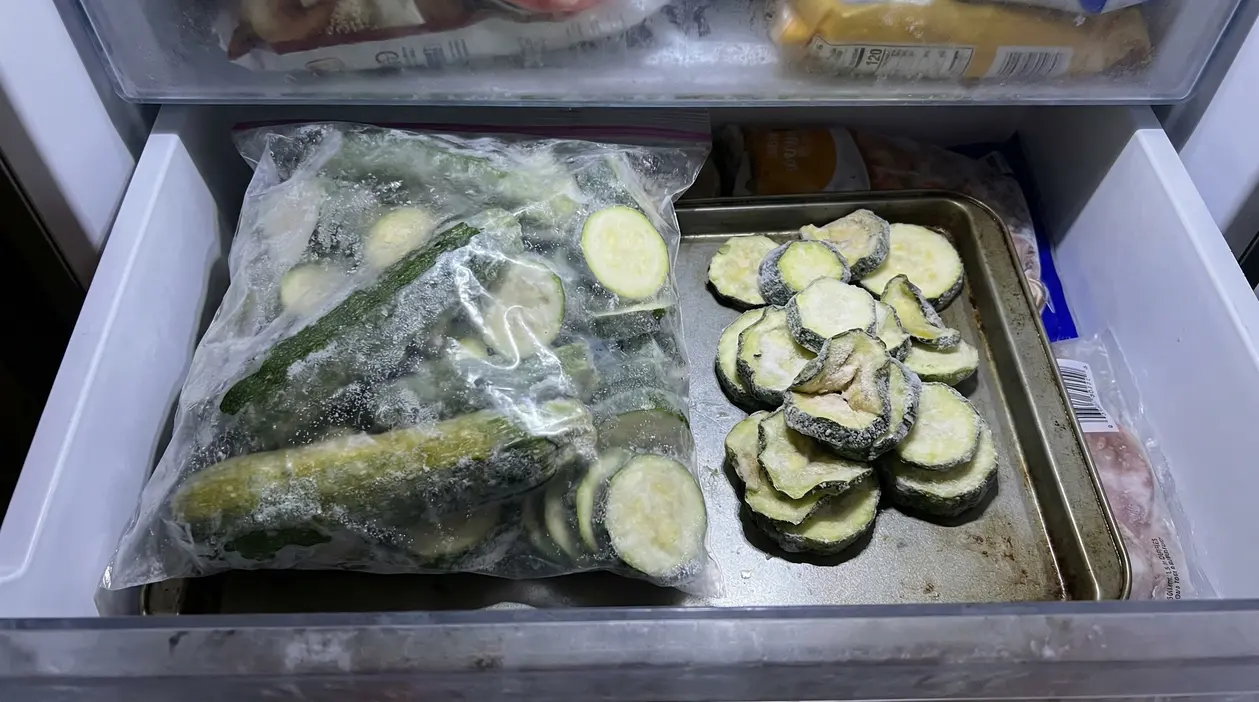 Zucchine affettate e surgelate conservate in un sacchetto e su una teglia nel congelatore