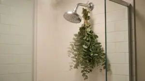 Mazzo di eucalipto appeso al soffione della doccia in un bagno con piastrelle bianche